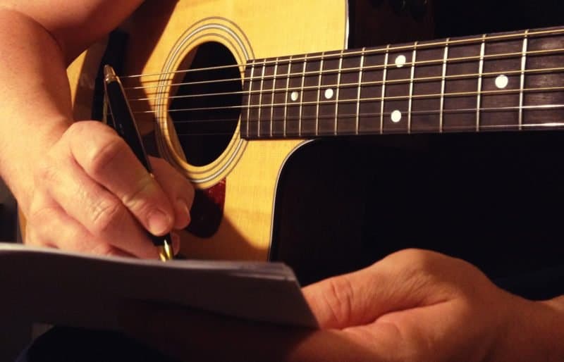 songwriter with a guitar and notepad