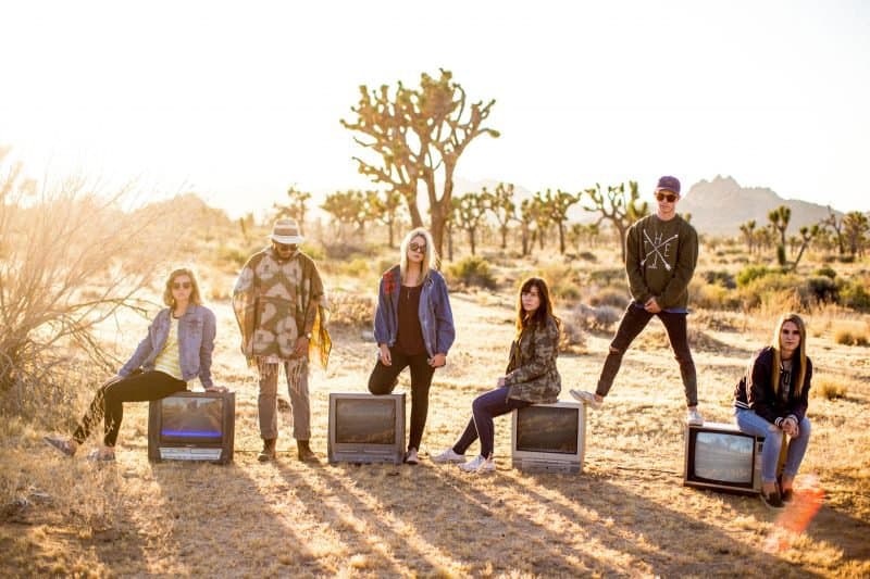 band photo taken in a desert with crt televisions