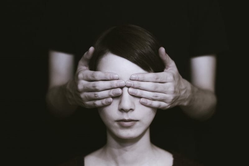 person with their eyes covered to symbolize mixing without a reference track