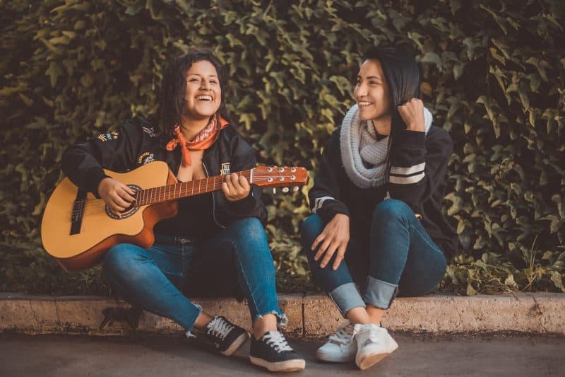 two people playing guitar outside