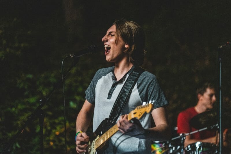 person singing and playing guitar on stage