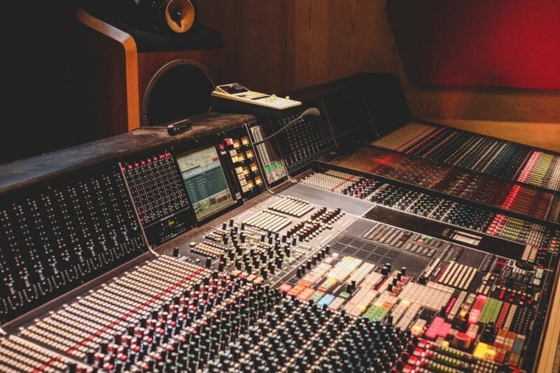 analog mixing console with faders, knobs, and outboard mixing gear