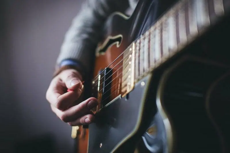 person playing a hollowbody guitar