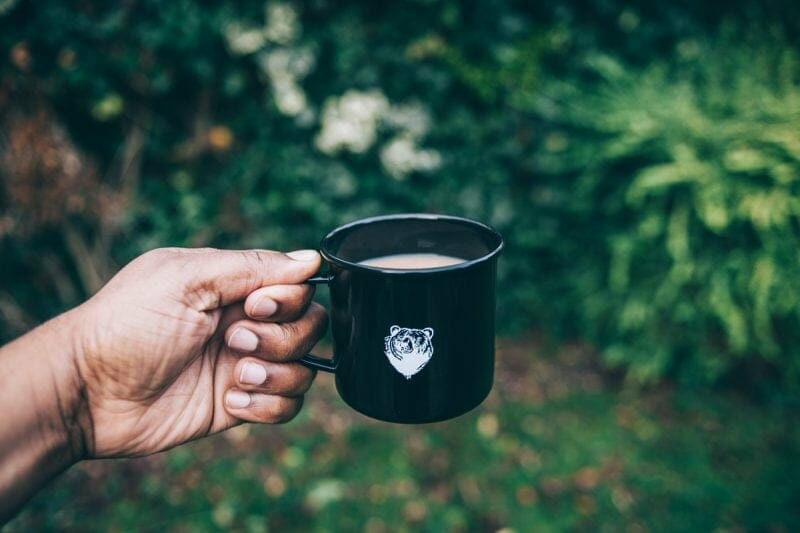 person holding a custom mug of coffee with a bear logo on it