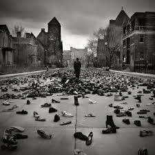 black and white songwriting prompt image of a person standing in a town square, surrounded by shoes