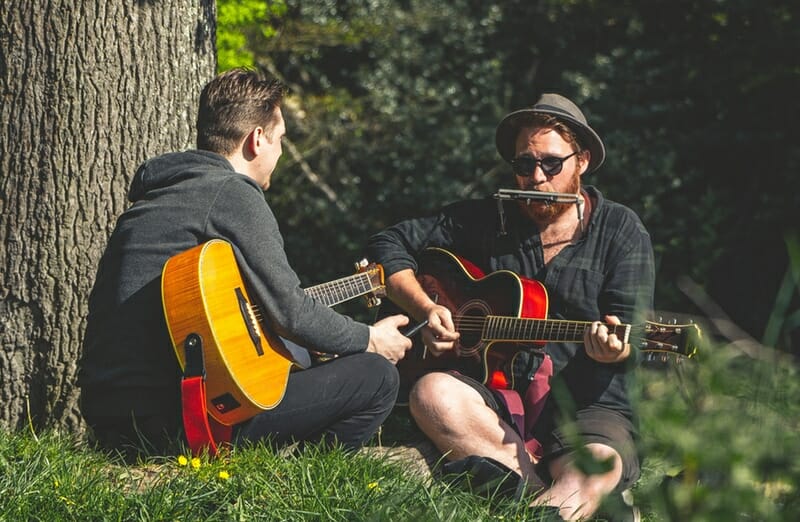 two musicians playing guitars outside